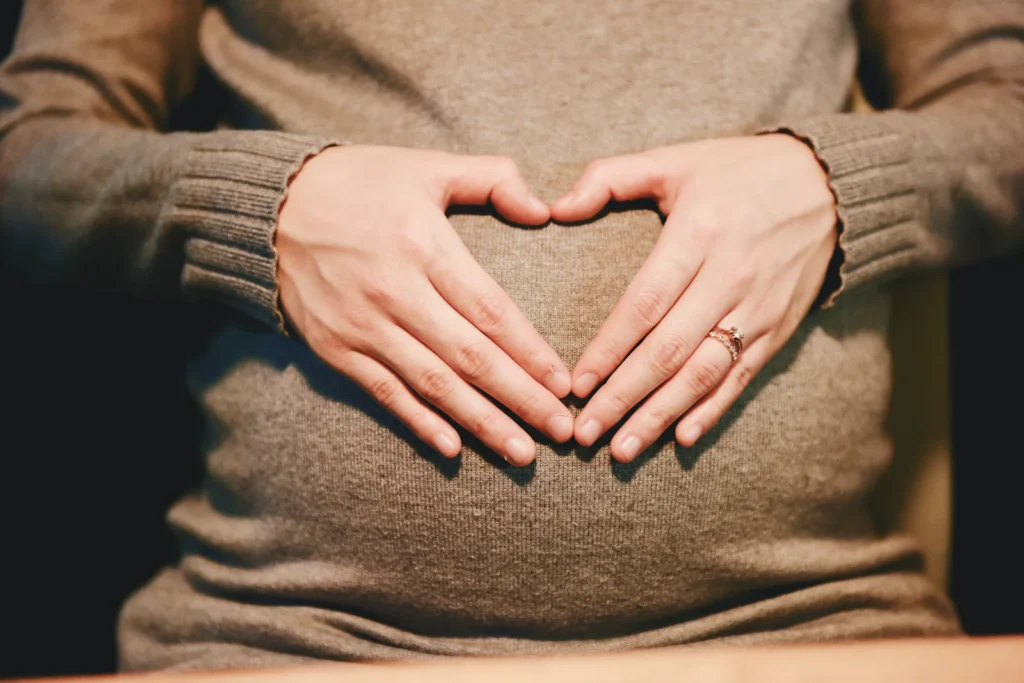 Mãos em forma de coração sobre a barriga de uma grávida